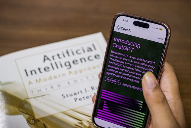 Tela de celular exibindo a home de uma inteligência artificial com âncoras de links destacadas, ao lado de um livro sobre visibilidade em IA.